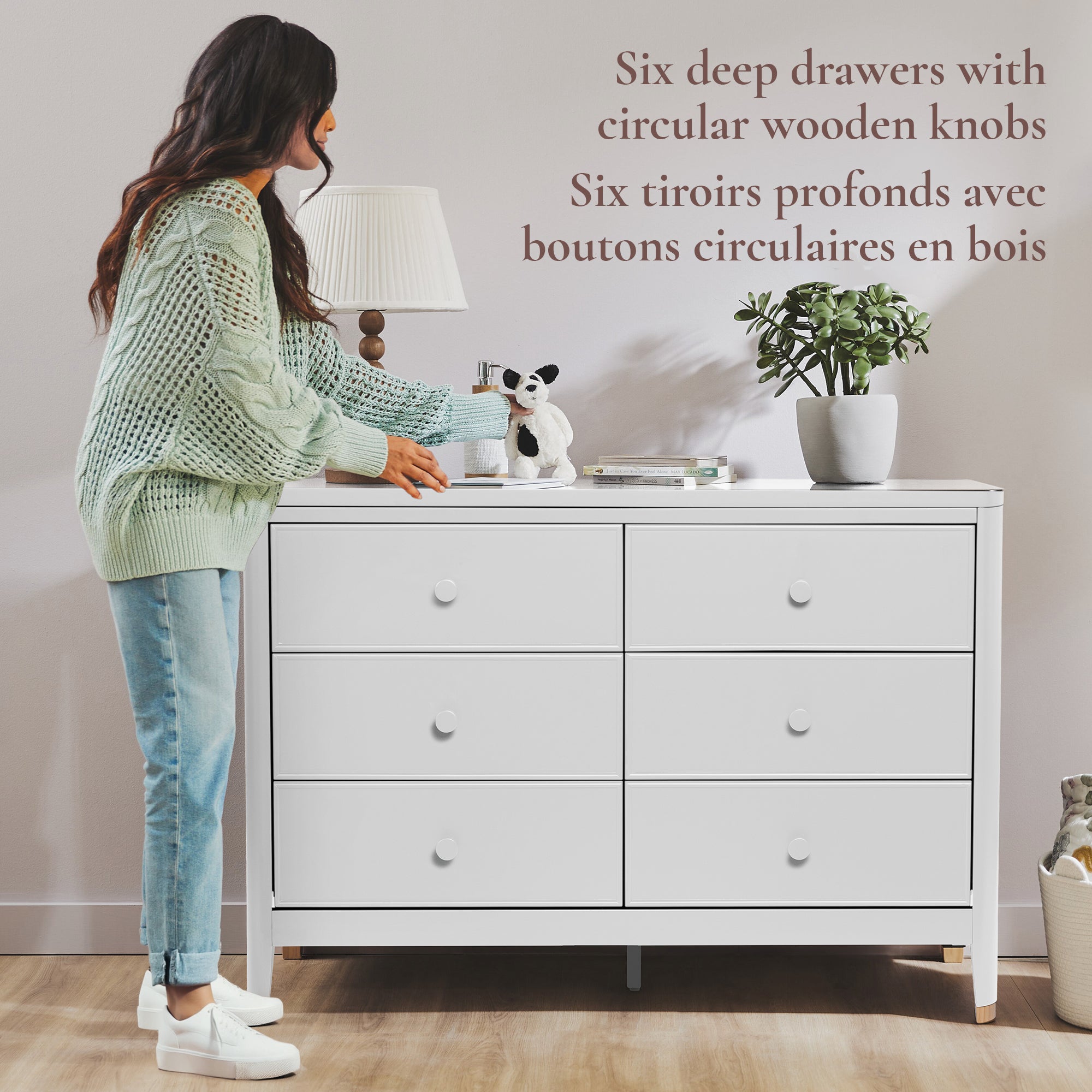 Woman reaching for a drawer on a white dresser with circular wooden knobs.