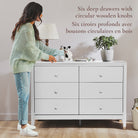 Woman reaching for a drawer on a white dresser with circular wooden knobs.