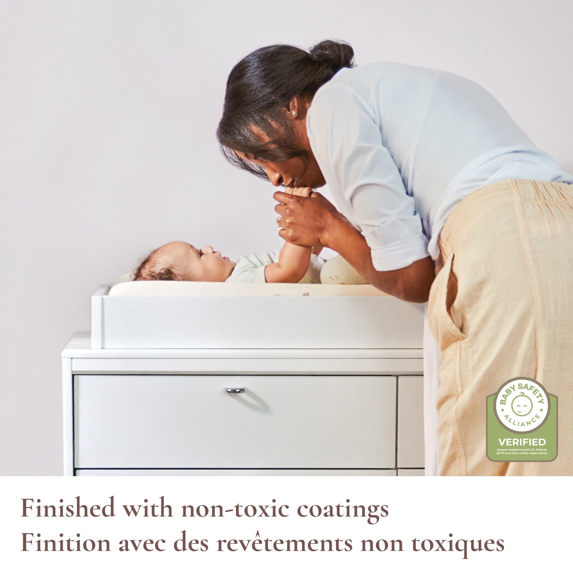 Lifestyle shot of a mom and baby featuring the non-toxic coating and Baby Safety Alliance verification.